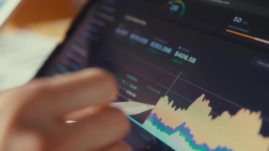 A close-up of a person using a stylus to analyze a fluctuating financial market chart on a digital tablet
