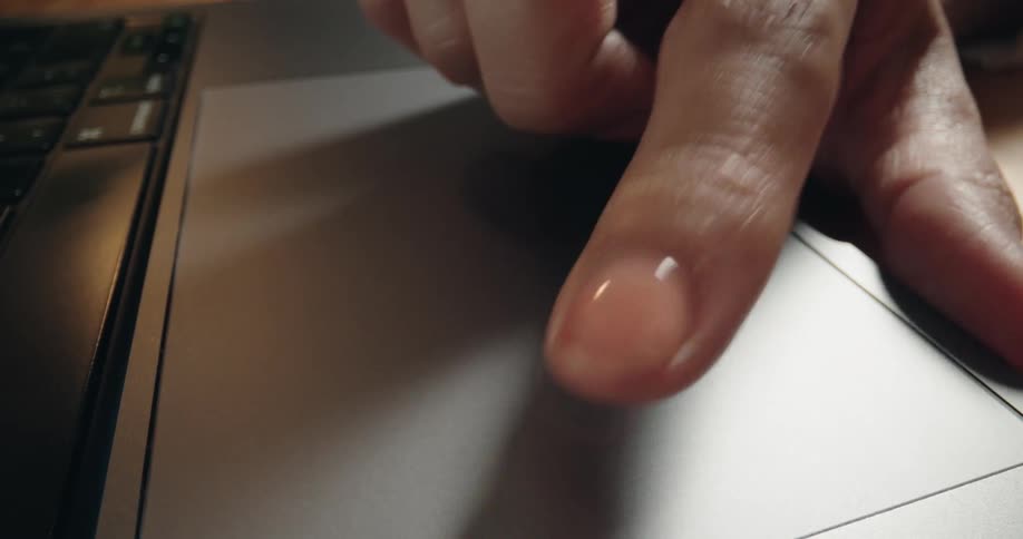 Extreme close-up shot of a finger scrolling and navigating on the grey trackpad of a modern laptop