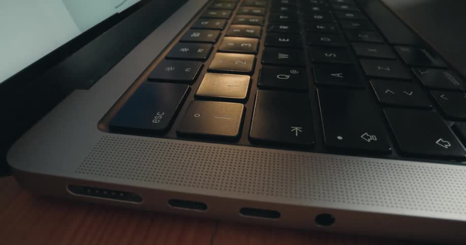 Extreme close-up macro shot of a finger repeatedly pressing the 'esc' key on a laptop computer