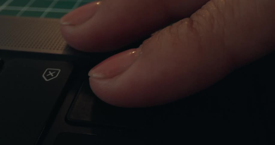 A close-up shot of a manicured finger pressing the enter key on a laptop keyboard