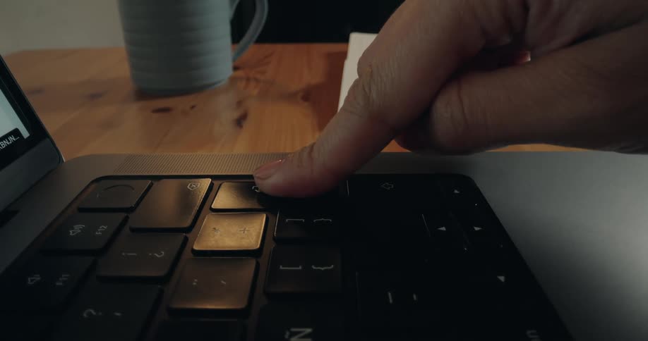 A dynamic close-up shot slides across a laptop keyboard before a finger presses the power button with a fingerprint scanner