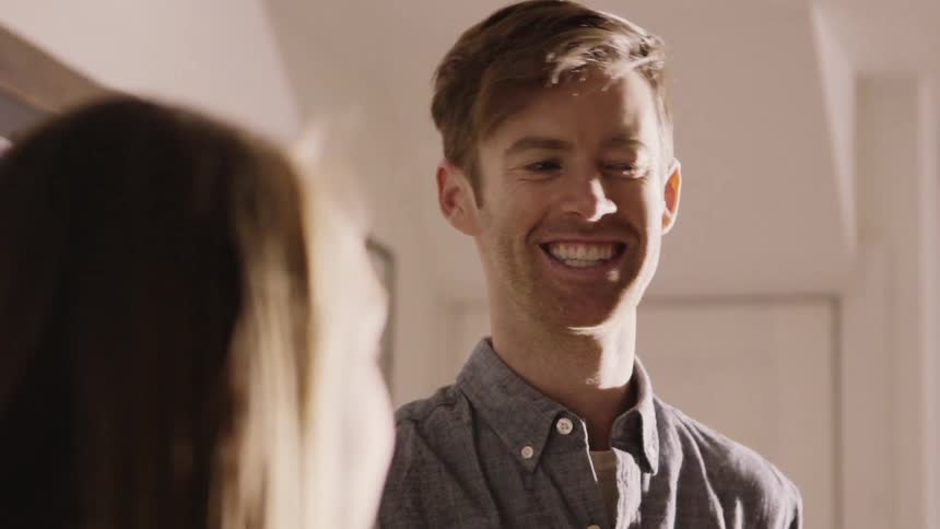 A man drinks wine while talking with a woman