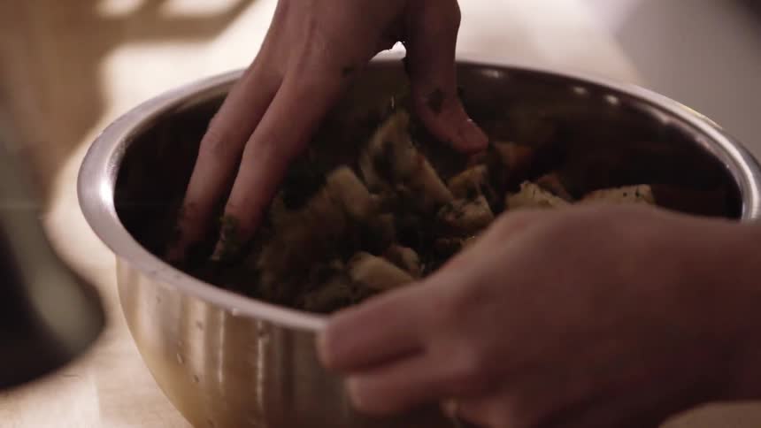 A person mixes food in a bowl with their hand