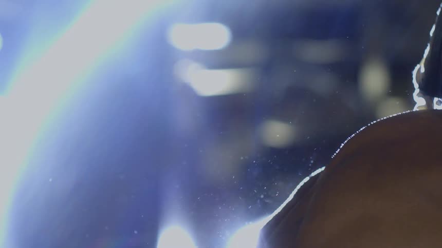 A boxer with red gloves and protective headgear stares intently forward in a dramatic slow-motion close-up