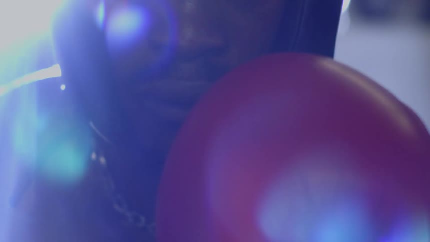 An intense boxer wearing a head guard and red gloves stares directly into the camera in a dramatic, slow-motion close-up
