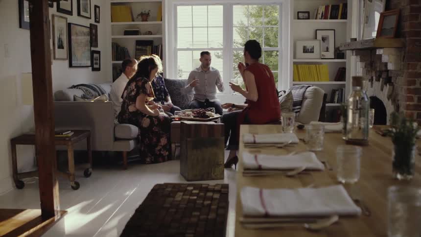 Group of people sit around a coffee table full of food