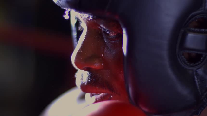 A dramatic close-up of a sweaty boxer's face in slow motion as a drop of sweat falls from his brow