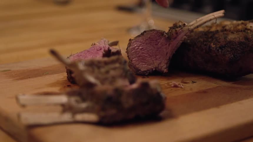 A woman is using a knife to cut cooked lamb