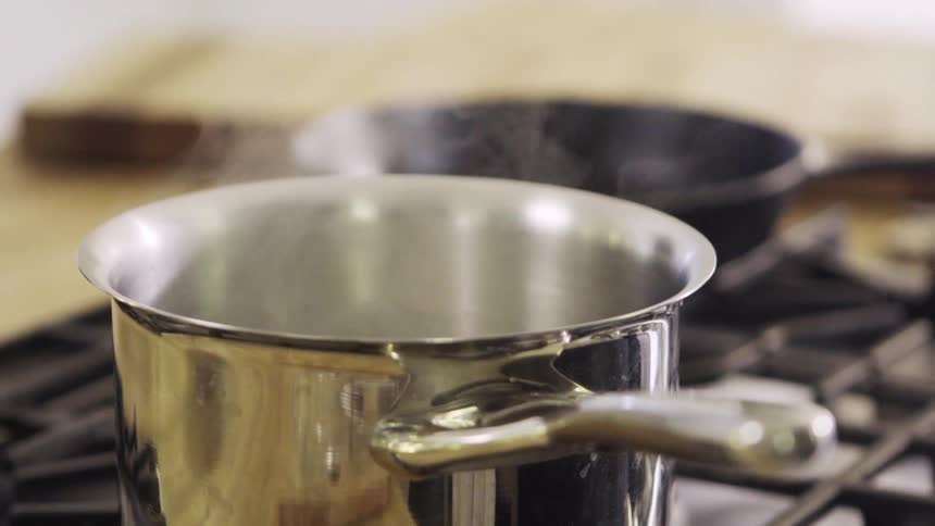 Steam rises from a pot sitting on a stove top