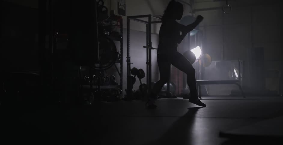 Woman practices boxing moves in a dimly lit gym
