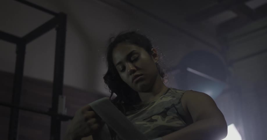 A woman wraps her hands in a gym