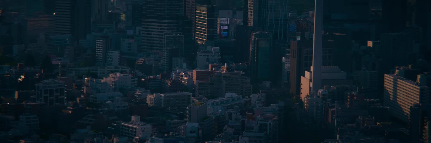 Golden sunrise light slowly moves across a vast and dense urban cityscape from a high-angle view