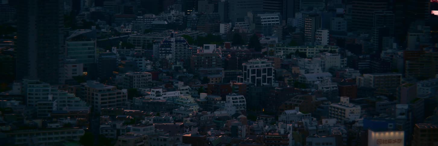 A wide, static high-angle view of a sprawling cityscape during the tranquil twilight hour
