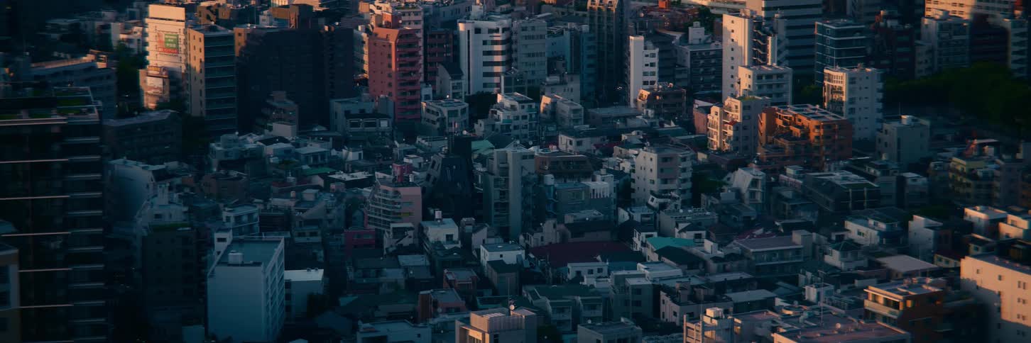 A static high-angle view of a dense Tokyo cityscape bathed in the warm, golden light of sunset