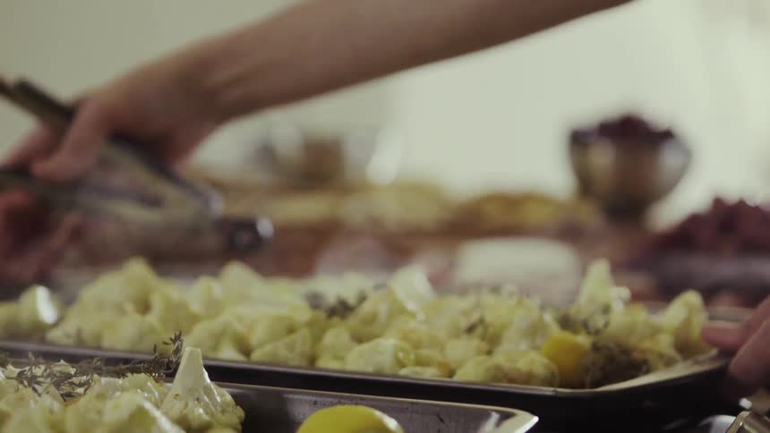 A person puts a tray of steaming vegetables on the burner