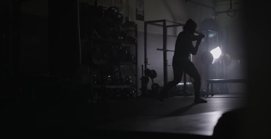 A woman spars and punches the air in a gym