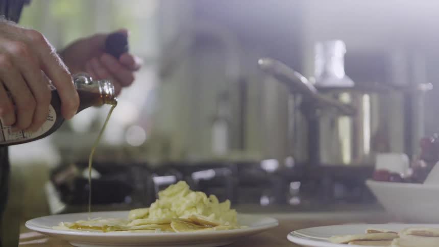 A man is pouring maple syrup over pancakes