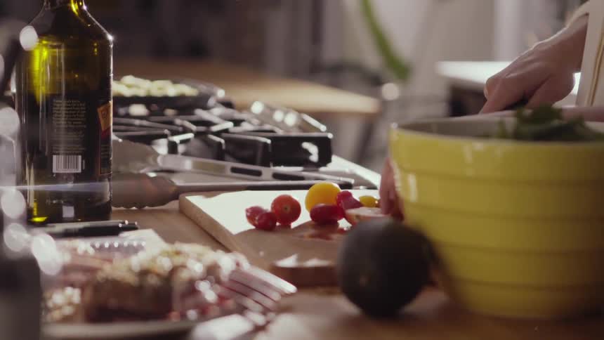 A person is cutting food and putting it in a bowl