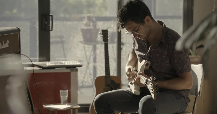 A man sits at home practicing guitar