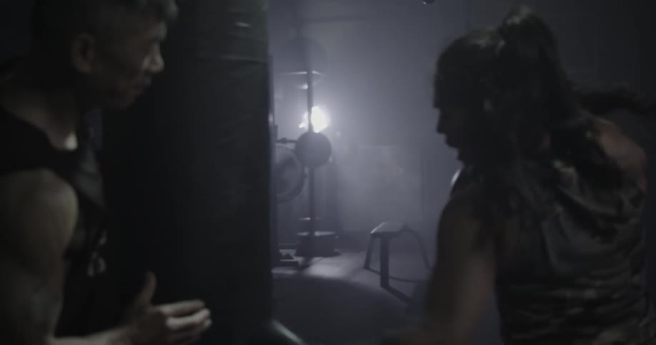 Man holds a punching bag while a woman punches it