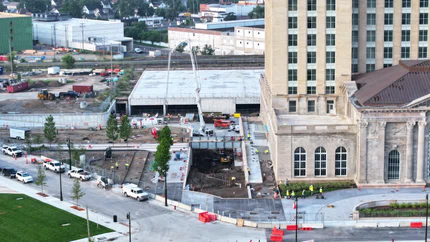 High-angle time-lapse shows a flurry of activity as construction workers and machinery operate at a large urban building site