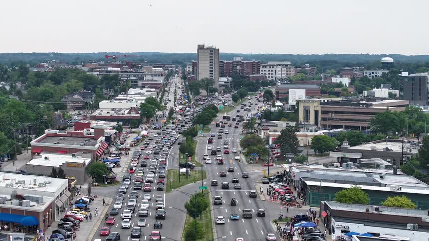 An aerial timelapse captures heavy traffic during a city car show, followed by a top-down view of an urban construction site