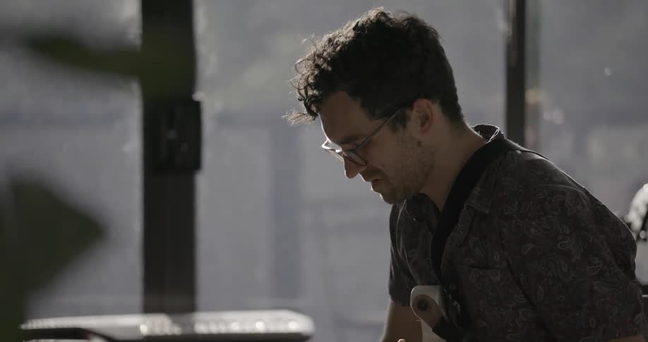 A man writes while holding a guitar