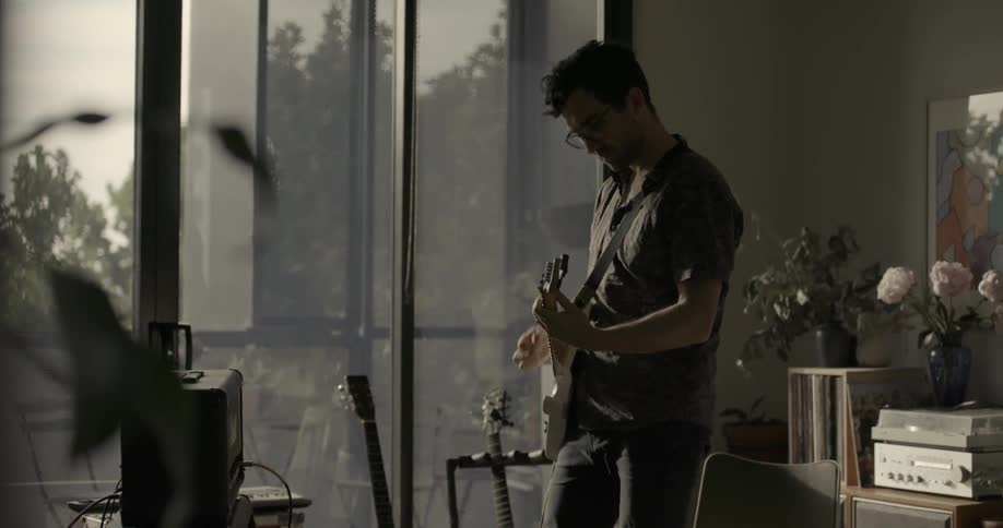 A man is standing in a room playing a guitar