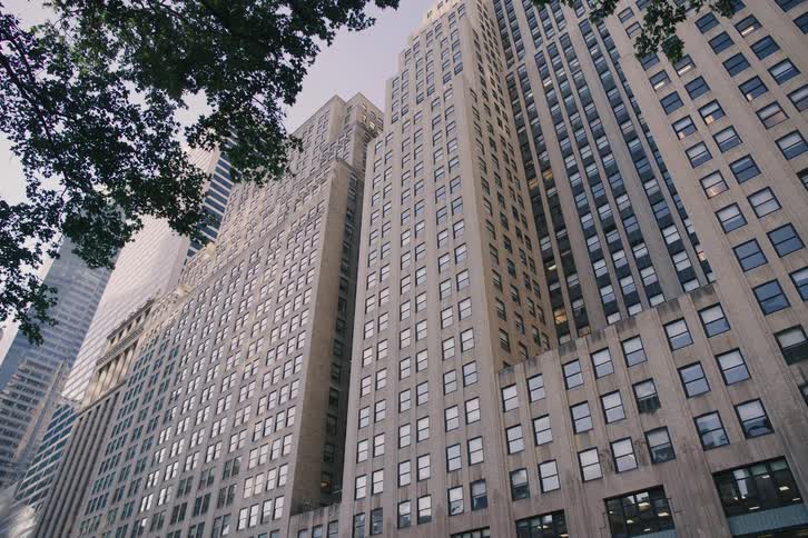 A slow upward pan reveals the impressive architecture of a classic skyscraper in a bustling downtown metropolis