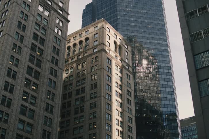 A low angle dolly shot reveals towering skyscrapers with diverse architectural styles in a dense urban cityscape