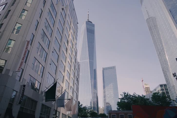 A low-angle pull-back shot reveals the iconic One World Trade Center skyscraper in New York City's financial district