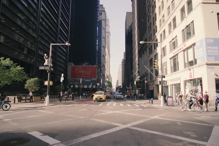 A slow tilt up from a busy New York City street corner reveals the towering skyscrapers against the bright sky