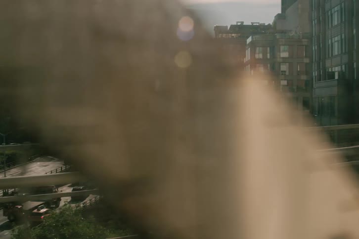 A cinematic view of the New York City urban landscape and traffic-filled highways as seen from a moving train crossing a bridge