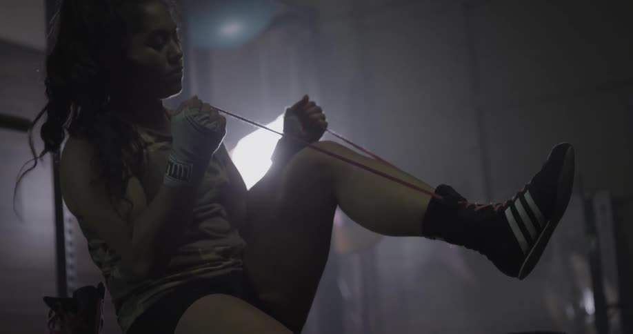 A woman laces up her boxing shoes