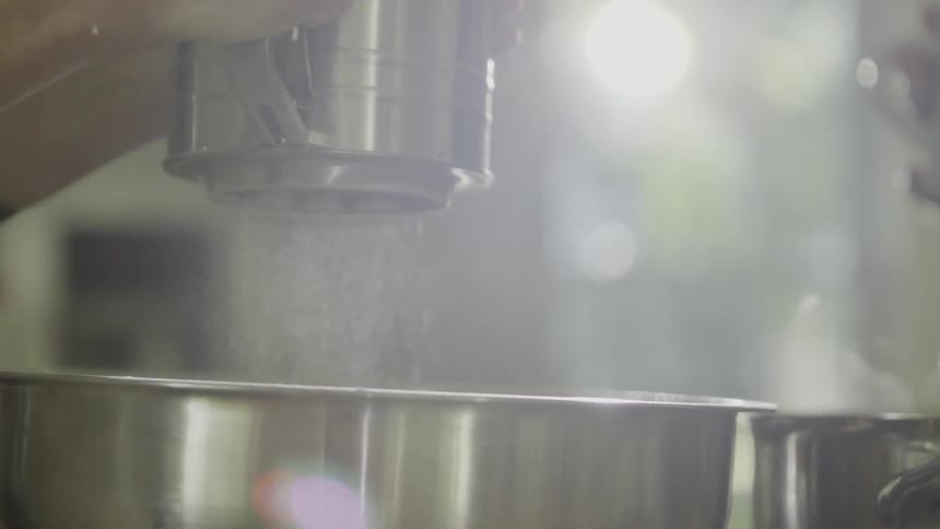 A person sprinkles spice into a pot