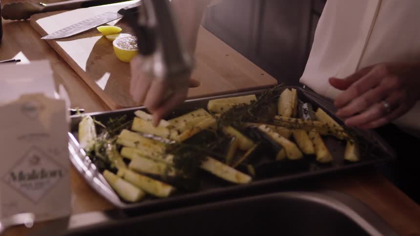 A woman is cutting a lemon and squeezing it in a pan