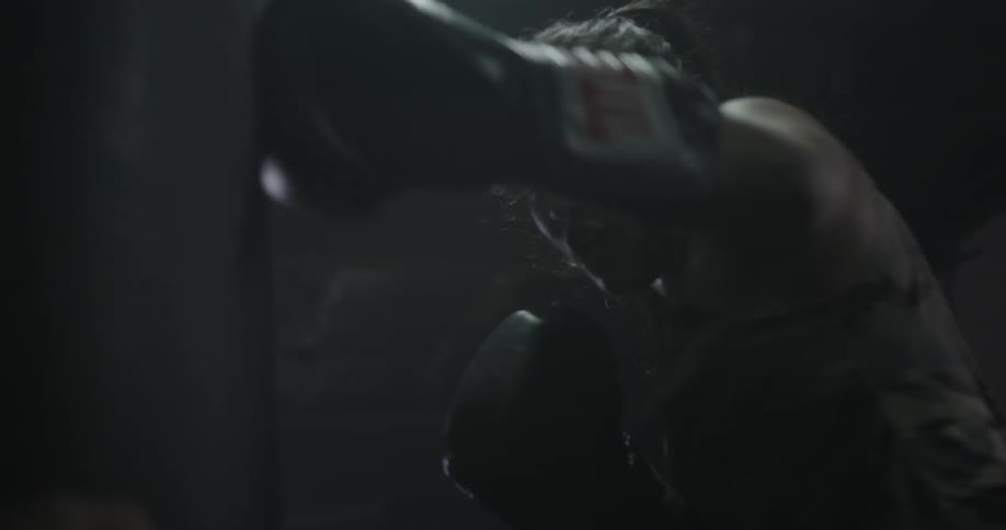 A woman is boxing punching a heavy bag