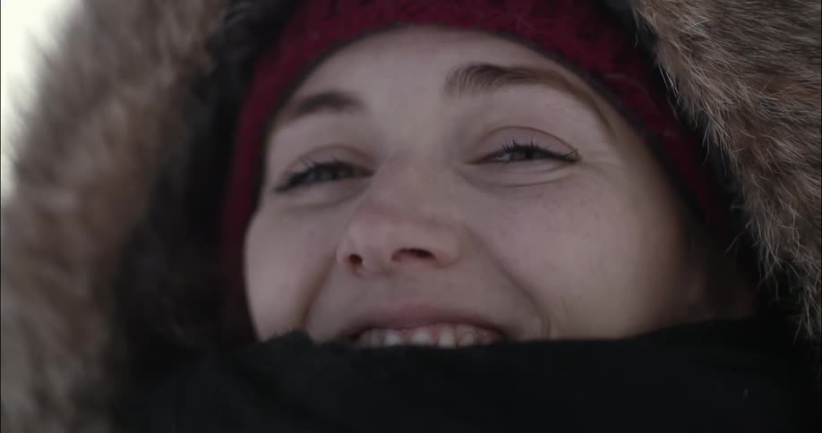 A woman smiles with a scarf around her mouth
