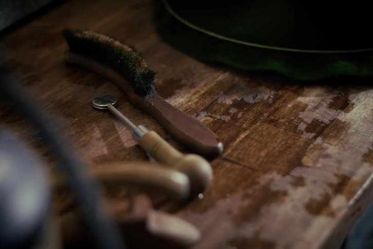 A vintage wooden brush and a small inspection mirror rest on a damp, dark wooden surface