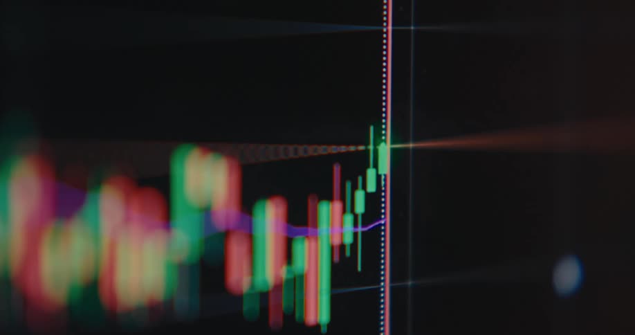 A shallow depth of field close-up captures a vibrant, fluctuating candlestick chart on a digital financial trading screen