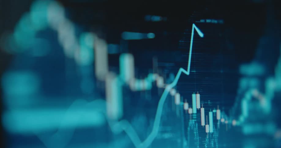 A digital screen shows a volatile stock market or cryptocurrency candlestick chart with a line graph fluctuating up and down