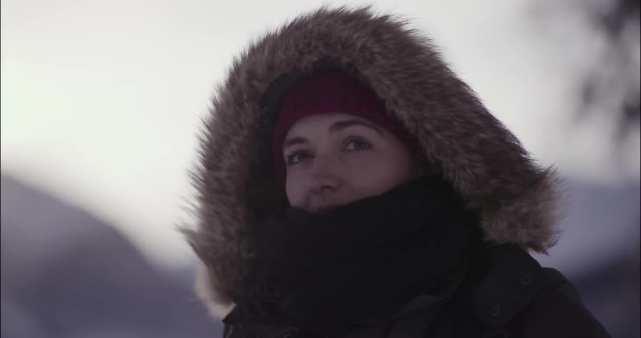 A woman has a large hood with fur on her head