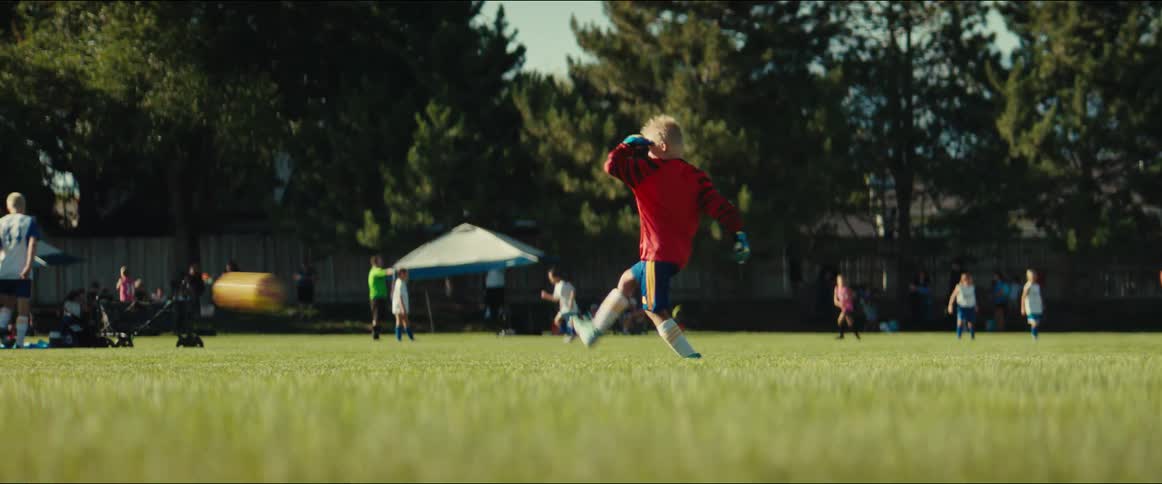 Focused young goalie kicks the ball downfield during a sunny youth soccer match