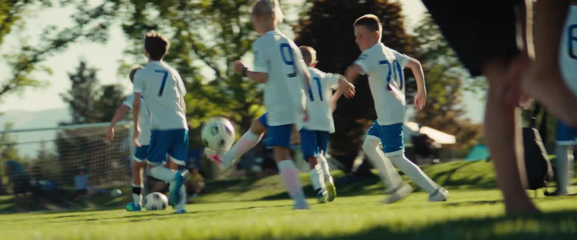 Youth soccer team running with their balls during a practice drill on a sunny day