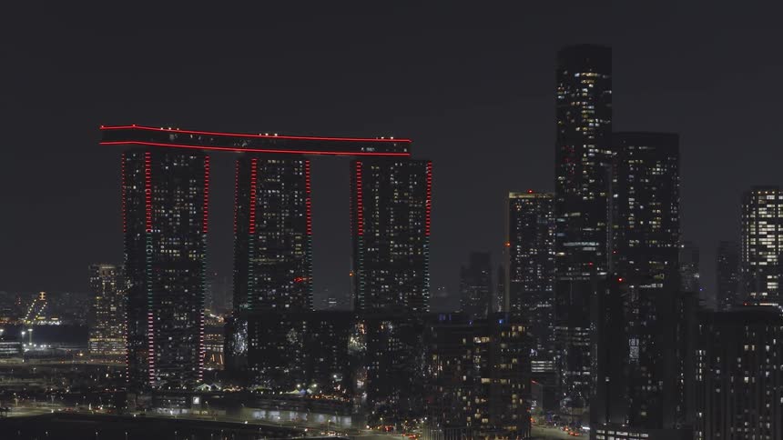 The iconic Gate Towers on Al Reem Island glow with red lights against the modern Abu Dhabi city skyline at night