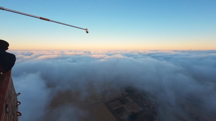 Stunning aerial view from a hot air balloon reveals a passenger looking out over a sea of clouds at sunrise