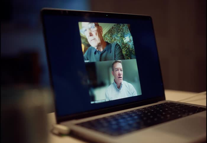 Close up of a laptop screen showing two men talking to each other during a video conference call