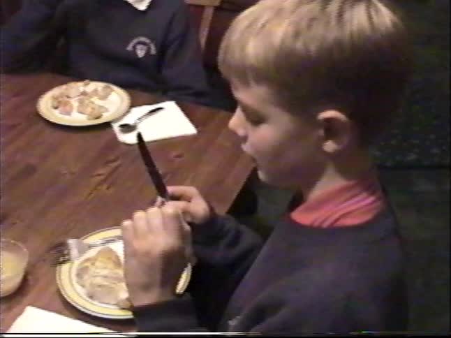 Vintage home video of two young brothers eating a meal together at a wooden dining table