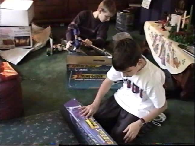 Two brothers smile as they unbox their new scooters and car toys on Christmas morning