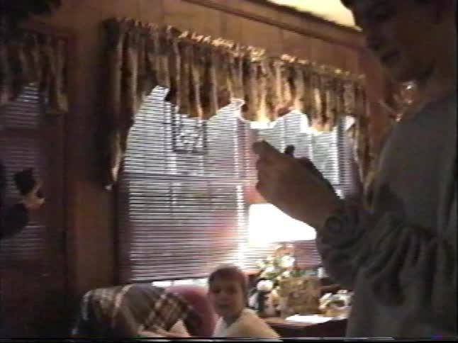 Vintage VHS footage shows a family gathering on Christmas morning, with a young boy looking at a gift he just received